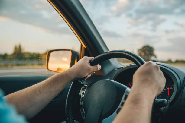 istock man driving car by highway on sunset 1061579844