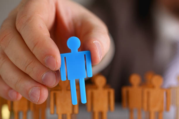 istock Man arm in suit take little plastic toy figure 1061597586