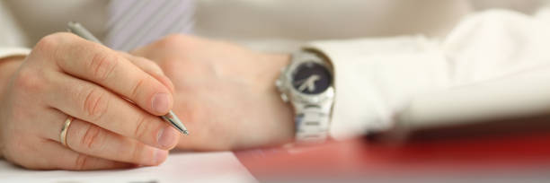 istock Male arm in suit and tie hold silver pen 1061597594