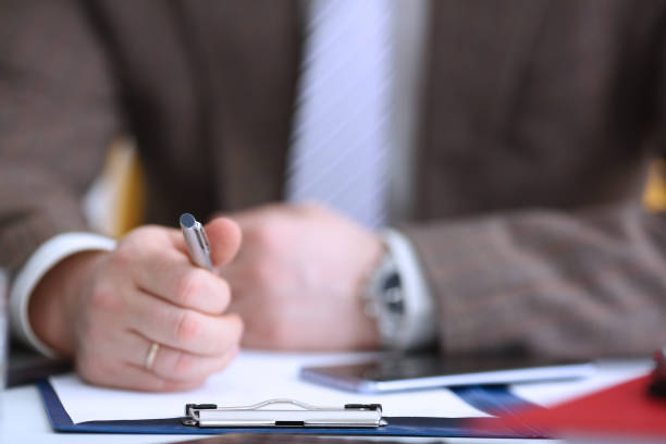 istock Male arm in suit hold phone and silver pen 1061597618