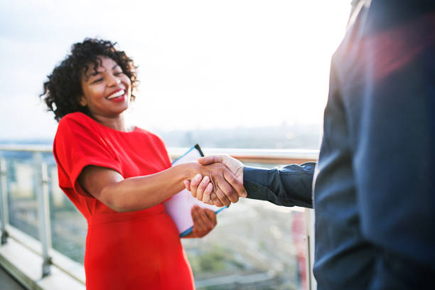 Two businesspeople standing on a terrace in London, shaking hands.
