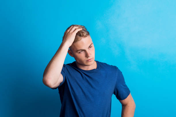 Portrait of a serious young man in a studio standing in a studio.