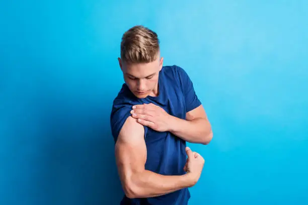 Photo of Portrait of a cheerful young man in a studio, flexing muscles.