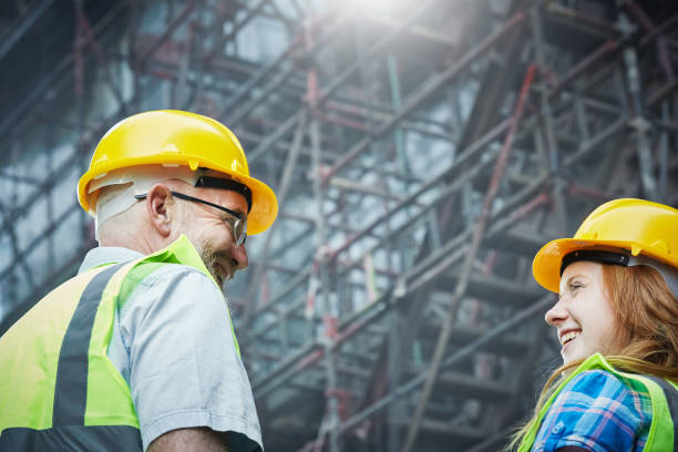 Male and female construction professionals smiling by scaffolding