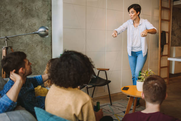 Friends Living Together Friends Living Together. Sitting in The Living Room, Having Fun and Playing Charades Together pantomime stock pictures, royalty-free photos & images