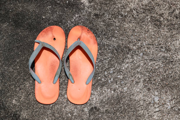 old and broken orange flip flops on street