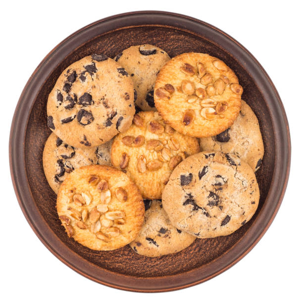 Cookies with peanuts and chocolate in a brown plate. Isolated on white background. Top view.