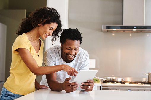 Cropped shot of a young married couple using a tablet together in the kitchen at home