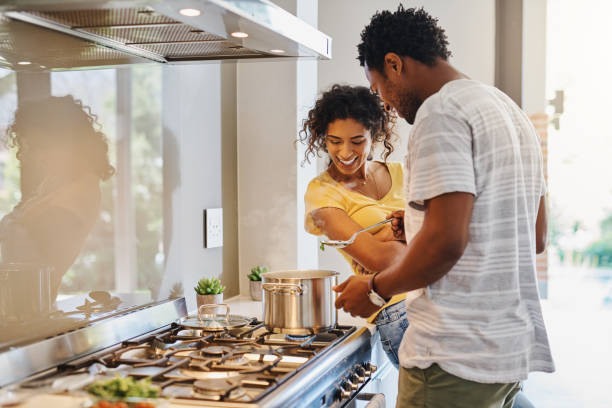Let's have a taste Cropped shot of a young married couple cooking together in the kitchen at home stove stock pictures, royalty-free photos & images