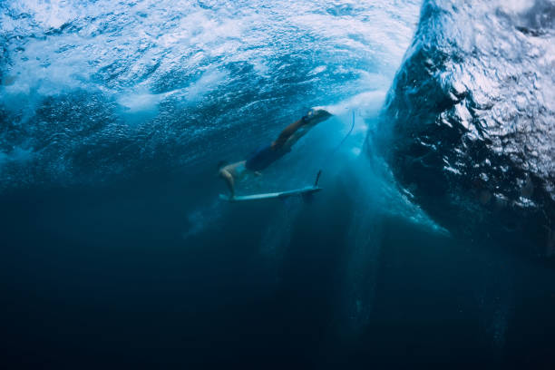 istock Professional surfer with surfboard dive underwater with big ocean wave. 1061638054