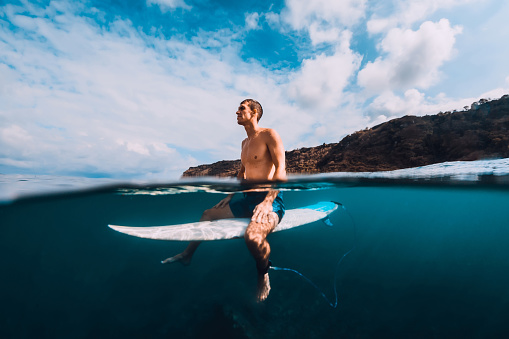 Surfer man with surfboard relaxing at line up in ocean