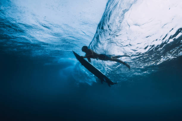 istock Surfer man with surfboard dive underwater of big ocean wave. 1061638150