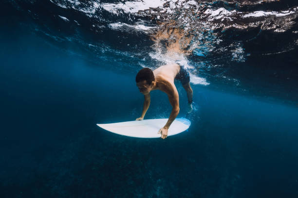 istock Man surfer with surfboard dive underwater of big ocean wave. 1061638168