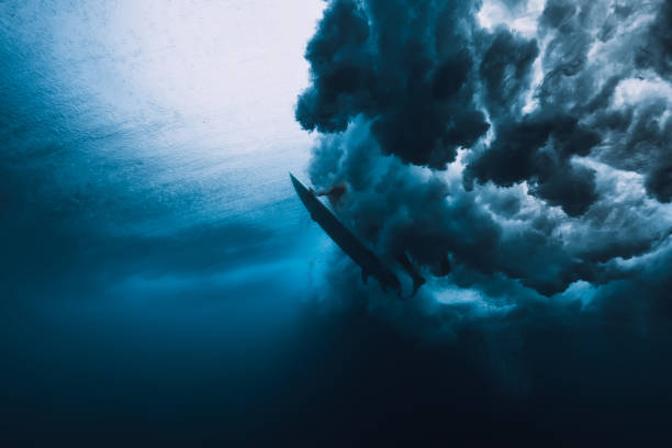 istock Surfer man with surfboard dive underwater with under big wave. 1061638202