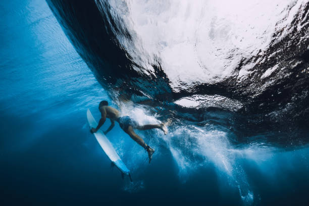 istock Surfer man with surfboard dive underwater. Alone surfer under big ocean wave. 1061638268