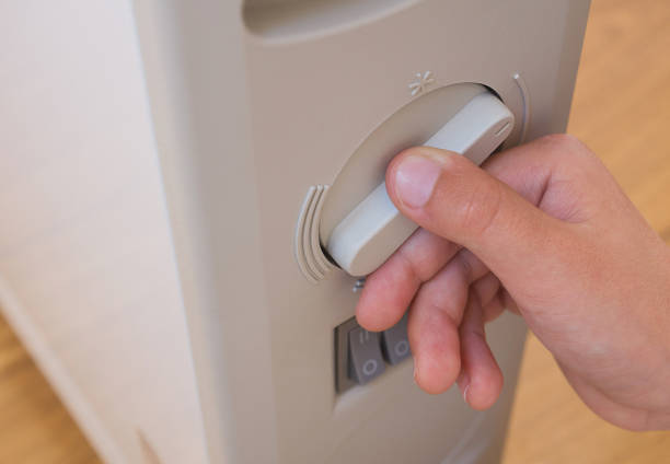 jeune garçon, réglage de température du chauffage électrique à la maison. gros plan, une partie du corps. - individual event photos et images de collection