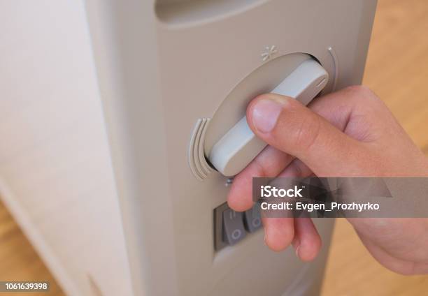 Photo libre de droit de Jeune Garçon Réglage De Température Du Chauffage Électrique À La Maison Gros Plan Une Partie Du Corps banque d'images et plus d'images libres de droit de Ajuster