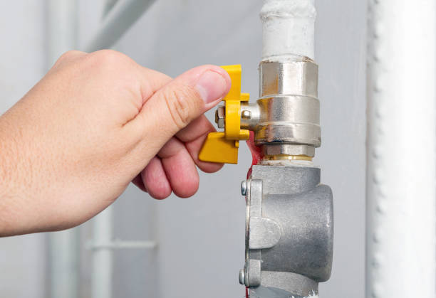 Person's hand opens or closes yellow gas valve on gas pipe at home. Symbolic image of natural gas savings in the heating season. Part of body, selective focus. stock photo
