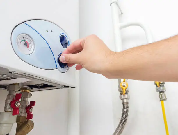 Man's hand turning the knob of gas boiler. Heating system at home.