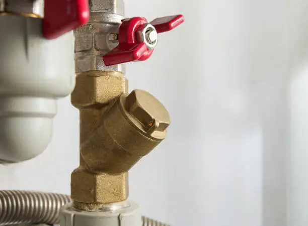 Photo of Water pipes with taps, filter and valves. Boiler room at home. Close-up, selective focus.