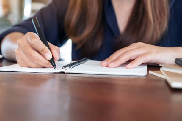 istock Closeup image of avwoman writing on blank notebook on table in cafe 1061641806