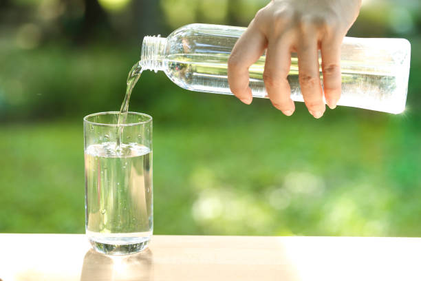 istock drink water pouring into empty glass with natural green background 1061642944