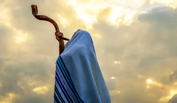 Jewish man in a tallith prayer shawl against dramatic sky