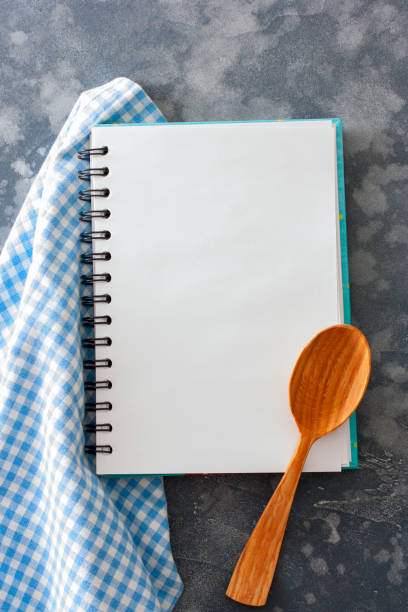 istock A clean culinary notebook with a blue napkin and a wooden spoon on the table, top view, copy space 1061645296