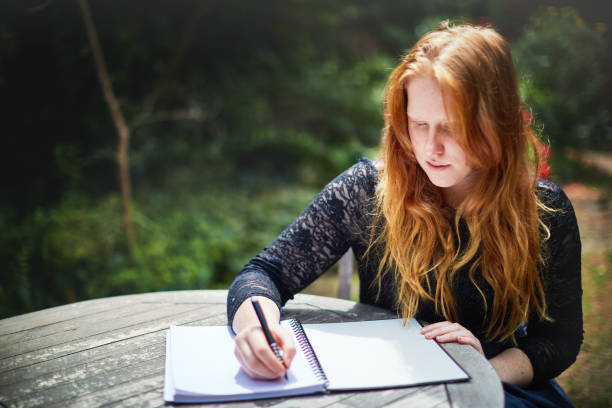 istock Beautiful young redhead writing at garden table 1061645382