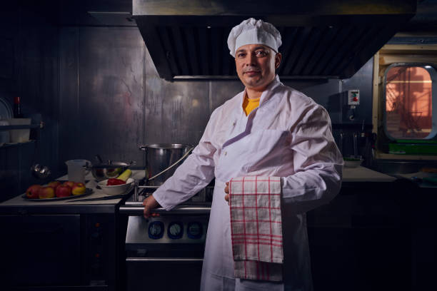 プロのシェフはキッチンで美味しい食事を prepairing 白いエプロンやコック帽子で調理します。 - commercial kitchen chef cooking food service occupation ストックフォトと画像