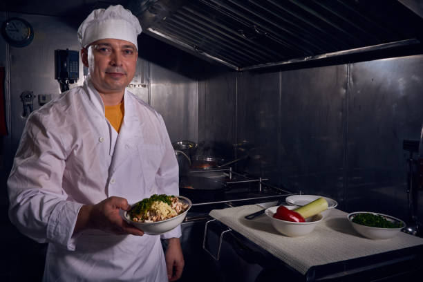 istock Professional chef cook in a white apron and cooks hat prepairing delicious meal on a kitchen. 1061645576