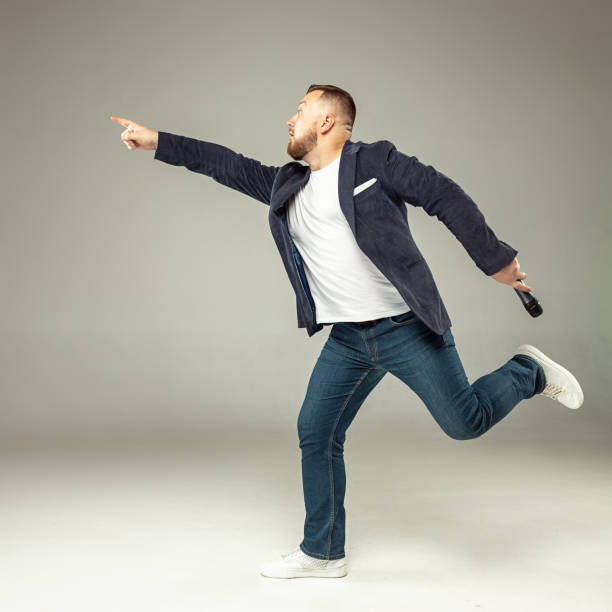 istock Young man with microphone on gray background, leading with microphone 1061647898