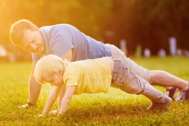 istock Little boy and his father doing plank exercise in sunny summer park 1061649306