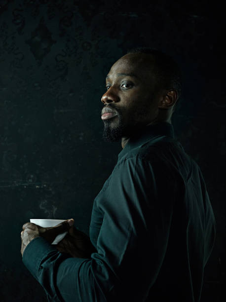 istock Stylish young black man with cup of coffee posing on dark background. 1061649510