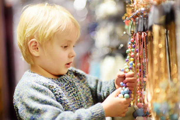 cute little boy helps his mom to choose jewelry in the accessories store - 7109 imagens e fotografias de stock