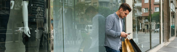 hombre joven con bolsas de compras y móvil - garment mannequin men store fotografías e imágenes de stock