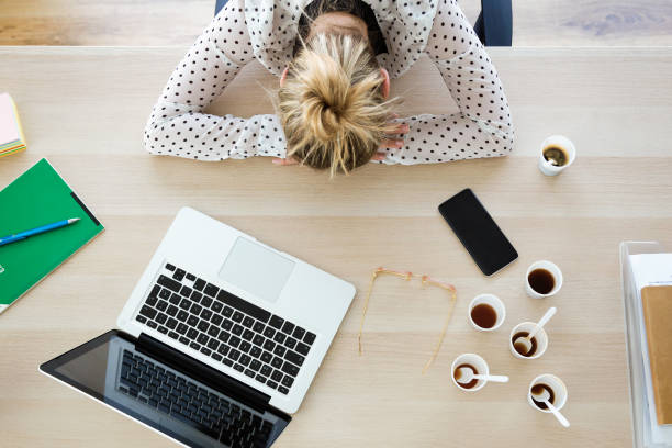 giovane imprenditrice stanca che dorme sulla sua scrivania in ufficio. - eccesso foto e immagini stock