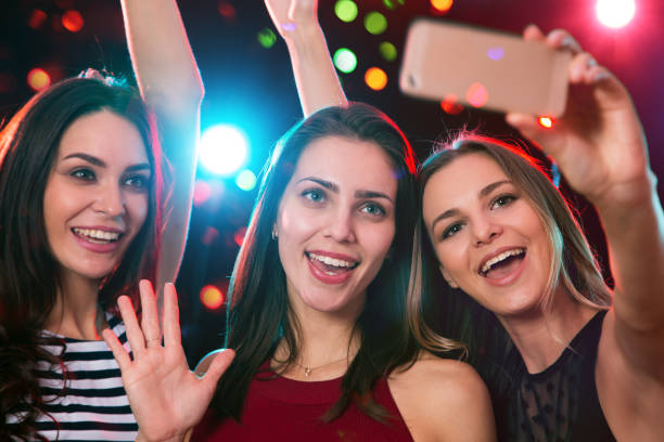 Smiling girls taking selfie in a night club stock photo