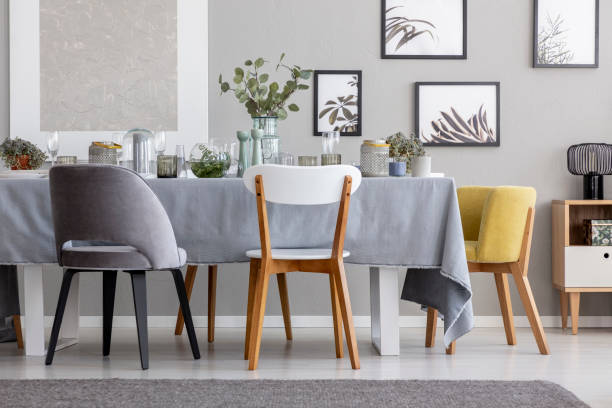 istock Modern chairs at table with tableware in grey dining room interior with posters and plants. Real photo 1061658736