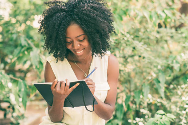 istock Happy young attractive black woman making notes in park 1061659882