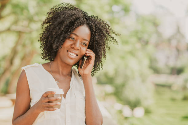 istock Smiling young black woman drinking coffee and calling on phone 1061659924