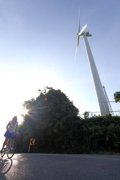 istock Woman bicycles past wind turbine 1061665934