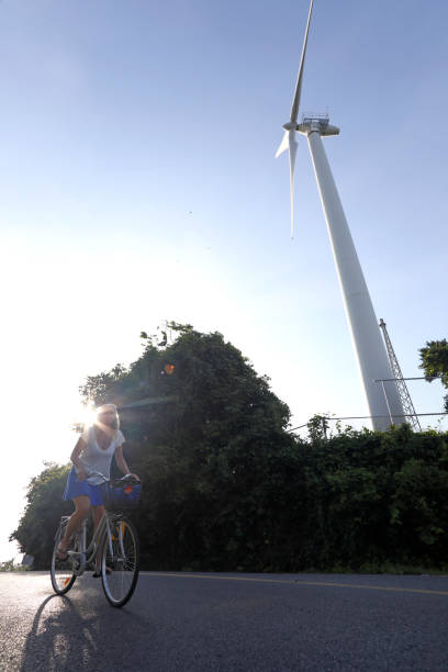 istock Woman bicycles past wind turbine 1061666182