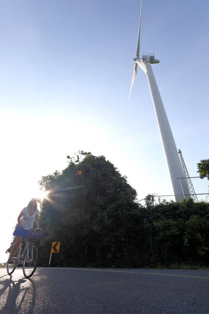 istock Woman bicycles past wind turbine 1061666184