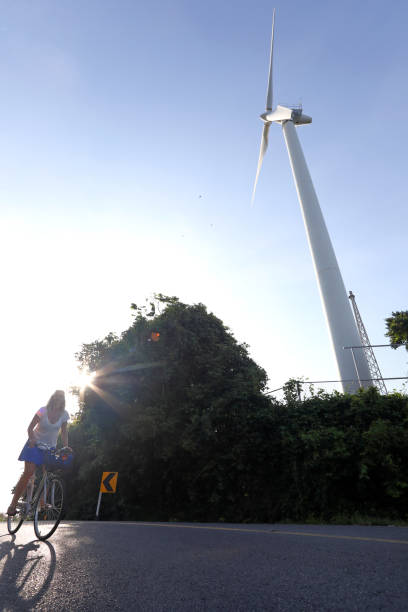istock Woman bicycles past wind turbine 1061666408