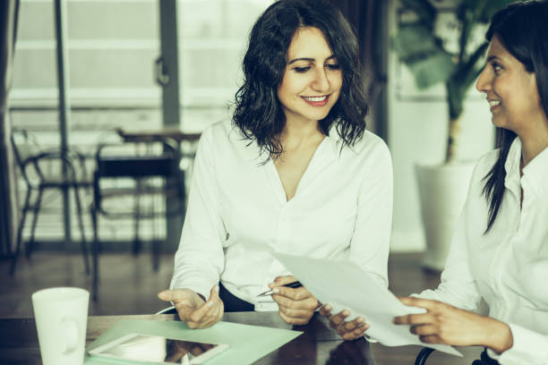 istock Two smiling female colleagues discussing documents in cafe 1061673218