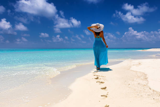 frau im blauen kleid geht an einem tropischen strand - footprint sand sea beach stock-fotos und bilder