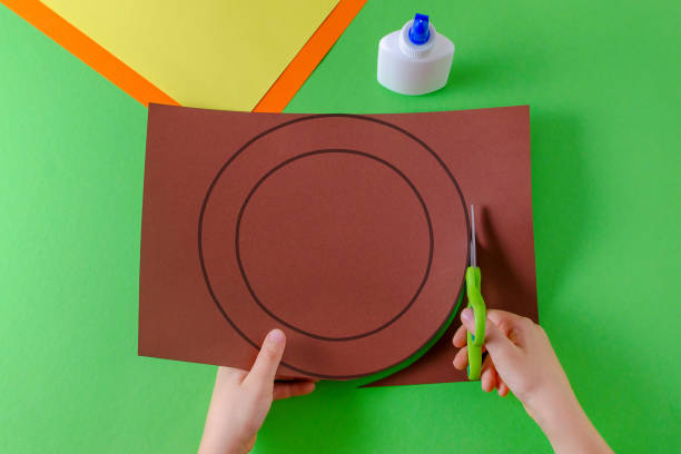 istock child's hands cut circle on brown paper with scissors, top view, on green 1061674574