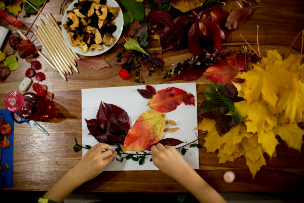 istock Children, applying leaves using glue, scissors, and paint, while doing arts and crafts in school 1061676814