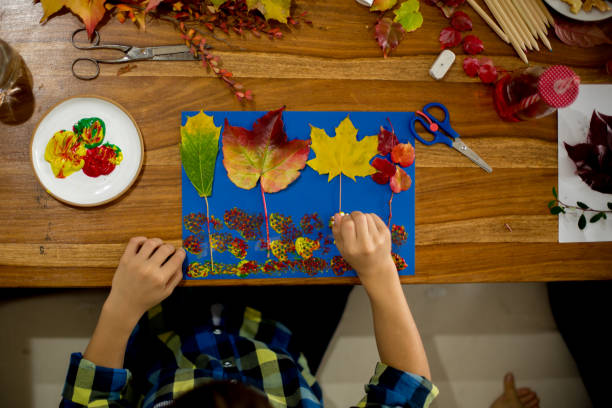 istock Children, applying leaves using glue, scissors, and paint, while doing arts and crafts in school 1061676848